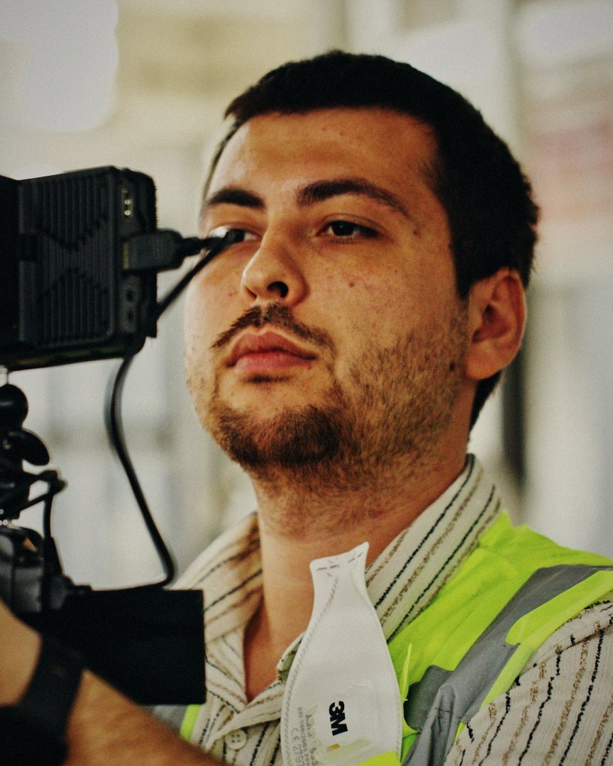 Recep Sefa Aktaş looking past a cinema camera on a factory floor